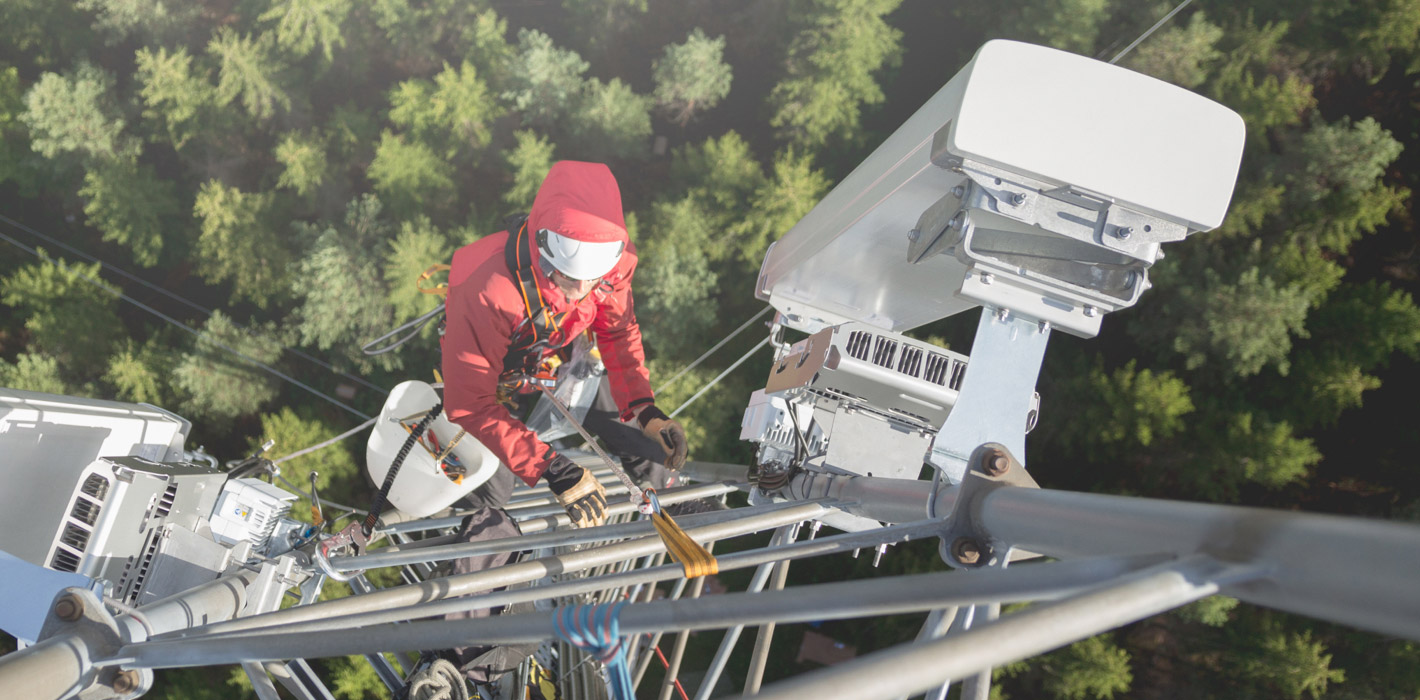 Men with red jacket climbing on a transmission tower