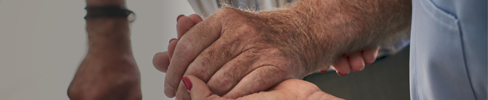 Elderly man's hand above younger's hand